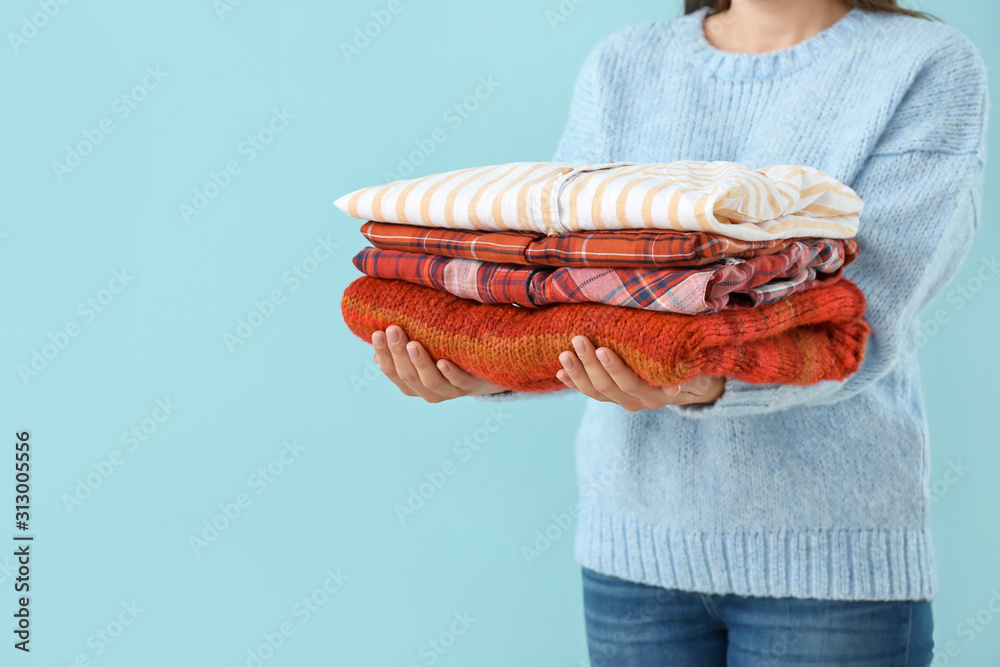 Young woman with clean laundry on color background