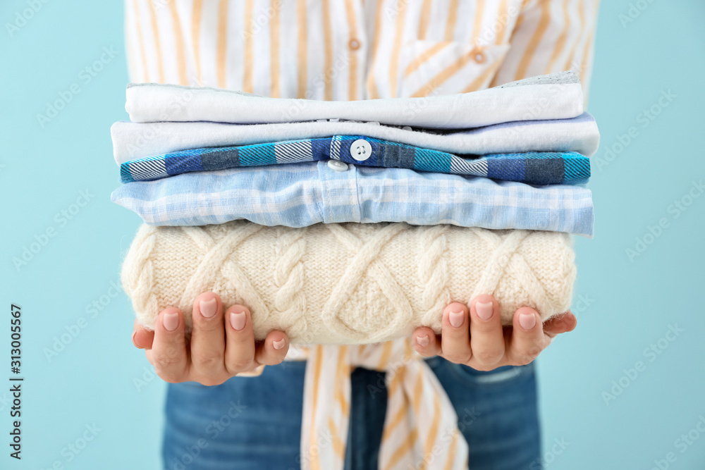 Young woman with clean laundry on color background, closeup