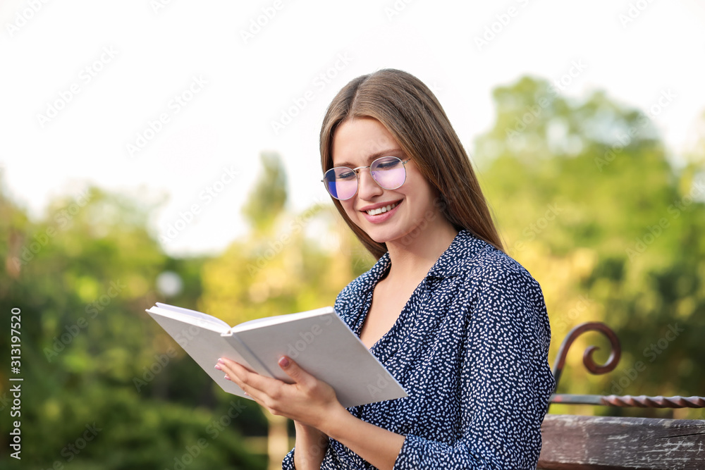 Beautiful young woman reading book in park