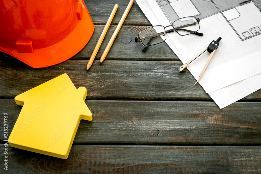 Builder helmet and blueprints on dark wooden background copy space