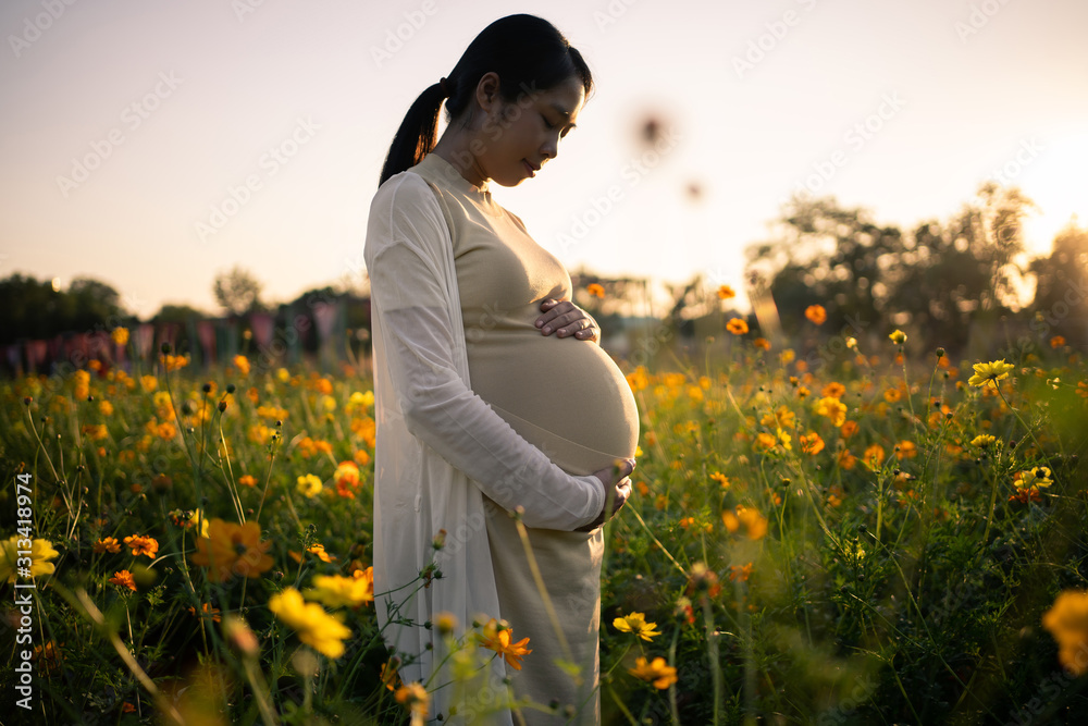 Pregnant woman is relaxing in the flower garden.