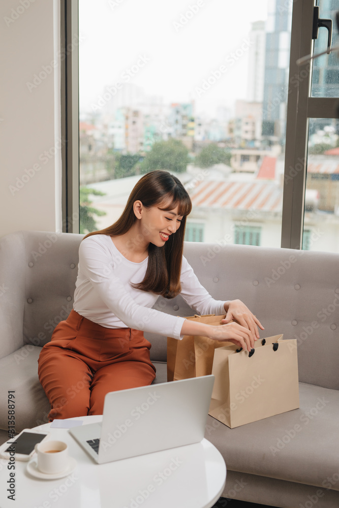 客厅里拿着购物袋的年轻亚洲女性。