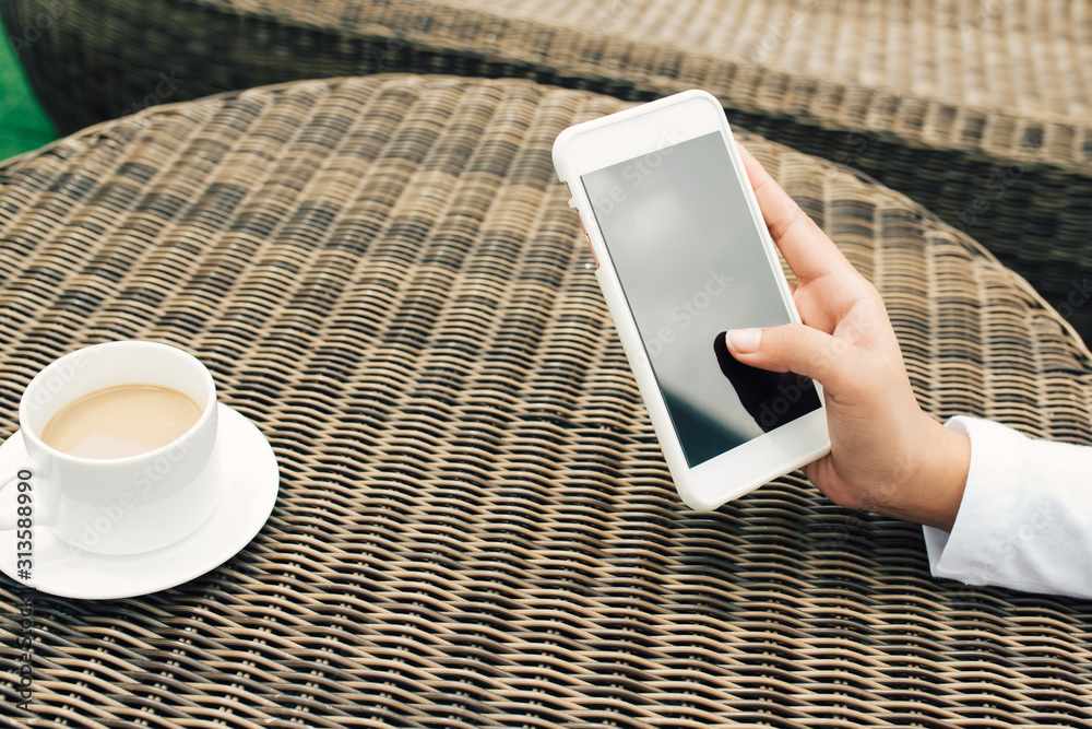 Hand holding White Smart phone on wood coffee table