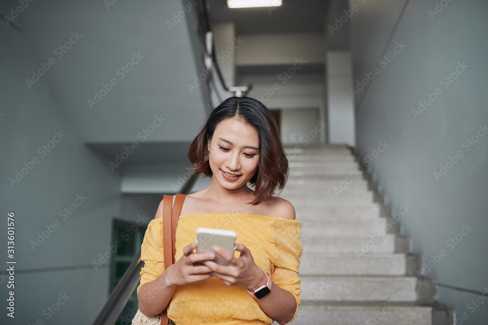 漂亮的亚洲成年女性走在楼下浏览手机