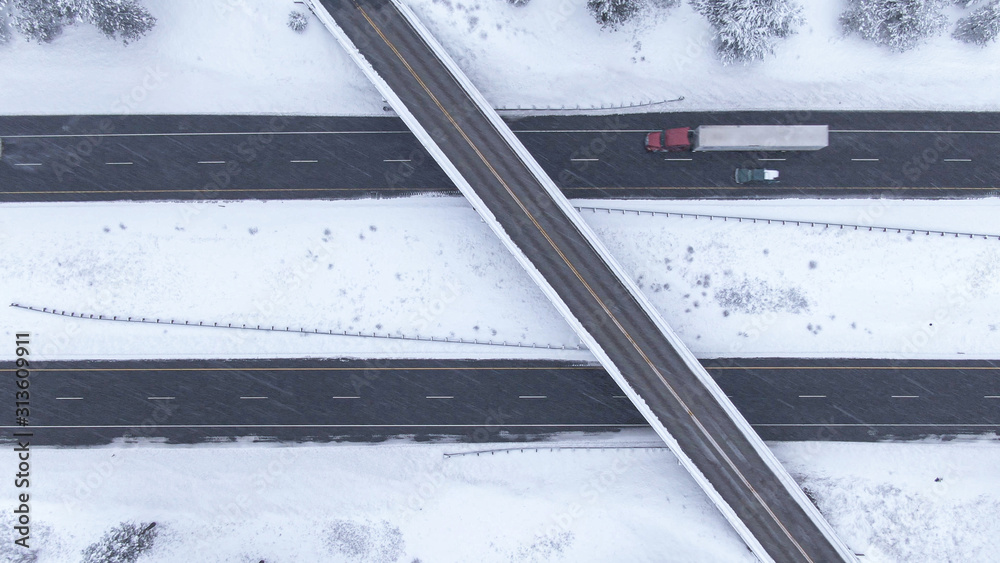 TOP DOWN: Flying above a highway overpass in USA during an intense blizzard.