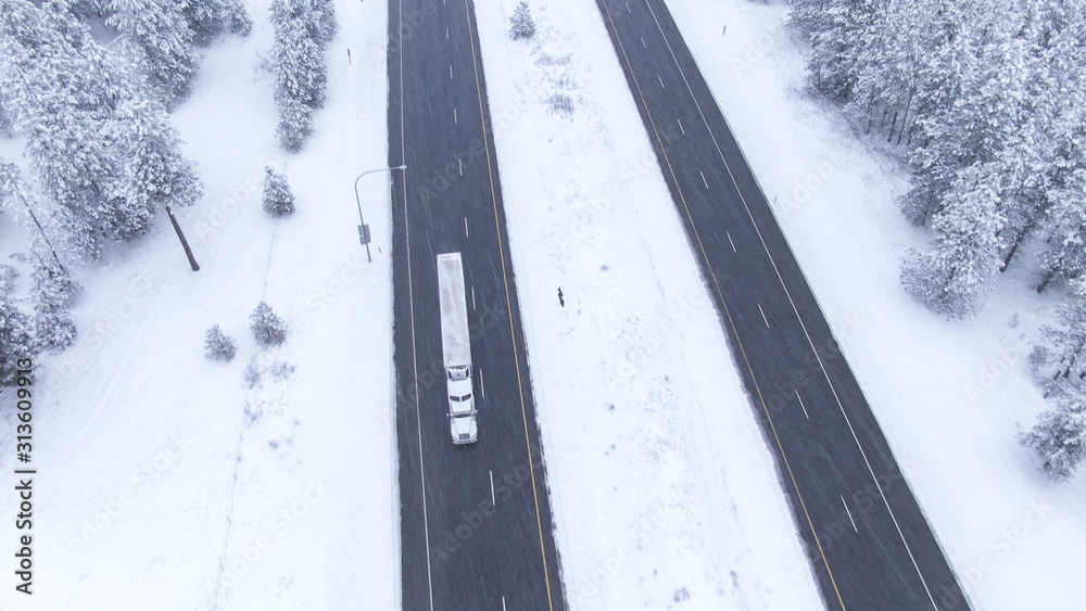 空中飞行：暴风雪中，一辆卡车在湿滑的高速公路上超速行驶。