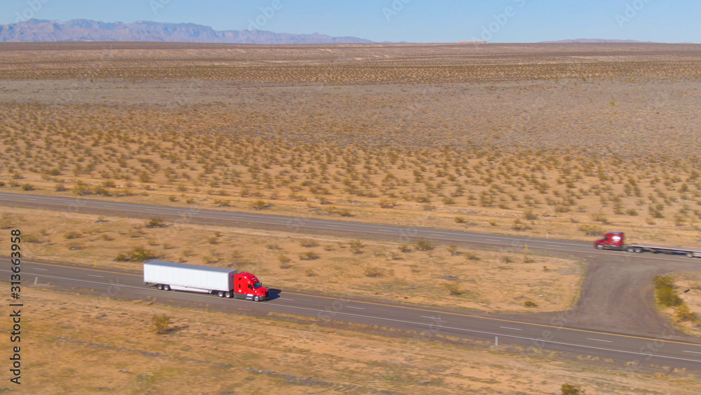 AERIAL: Flying above a red cargo truck enduring a long drive across Utah desert.