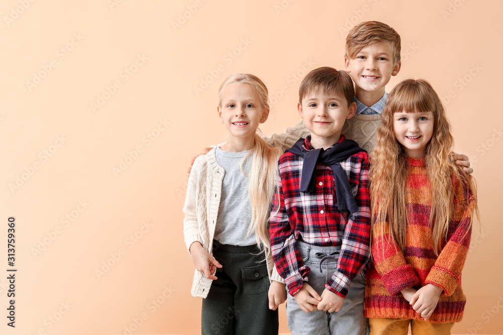 Cute little children in autumn clothes near color wall