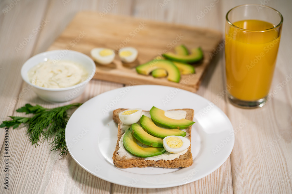 Breakfast avocado and egg toast, orange juice on wooden table. Healthy breakfast