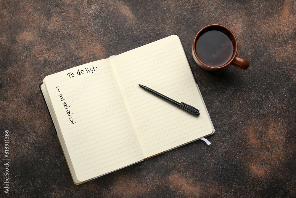 Notebook with blank to-do list and cup of tea on dark background