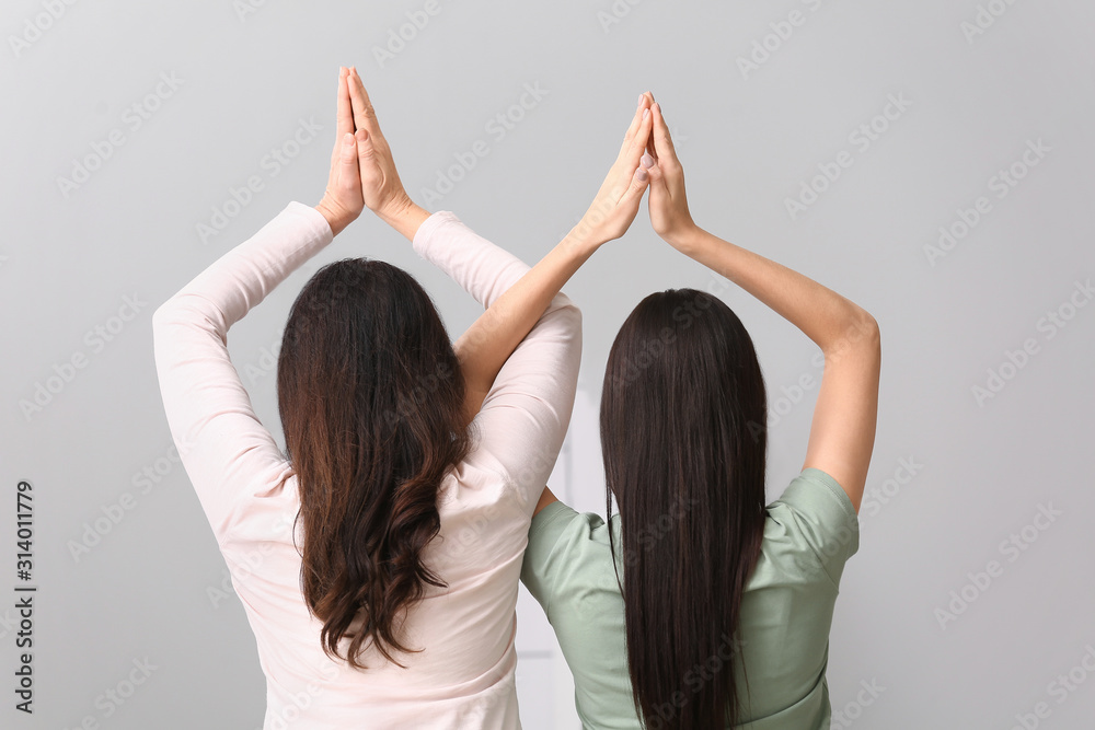 Mature woman and her adult daughter doing yoga together at home