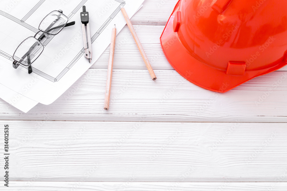 Builder helmet and blueprints on white wooden background copy space