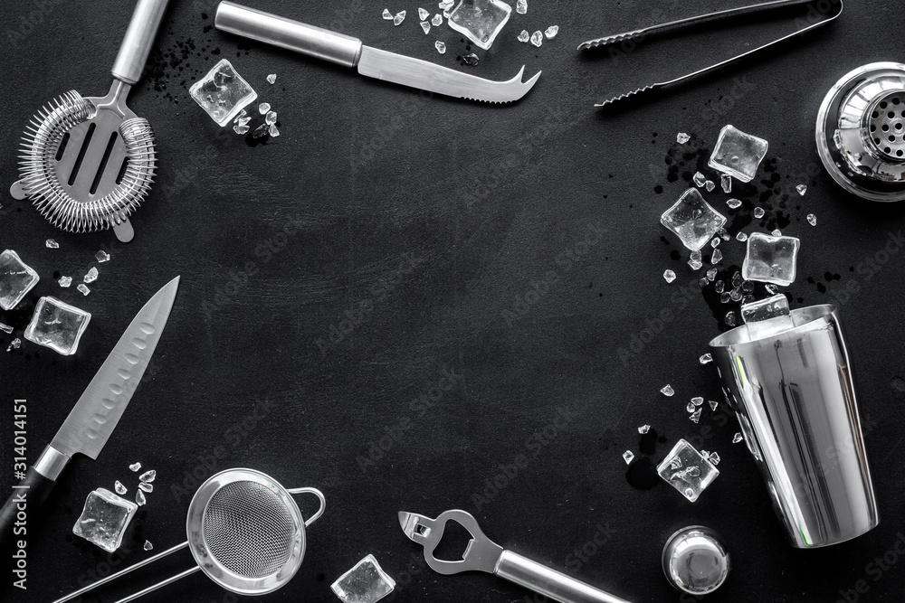 Bar utensil, tools - shaker, stainer - near ice cubes on black background top-down frame copy space