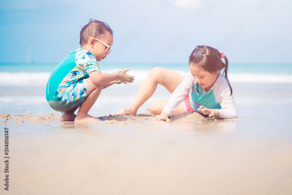 5.10 years old Little asian girl playing on the beach with her 2.9 year old baby brother.Family with