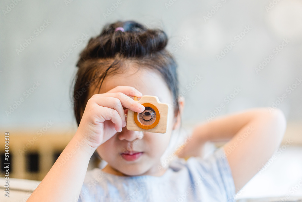 Little asian girl holding Wooden toy camera and take picture.Concept for photography, Photo Educatio