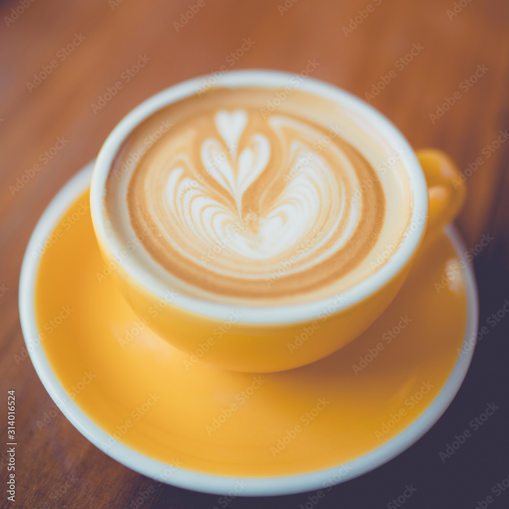 Coffee latte art in coffee shop on wooden table in the morning.