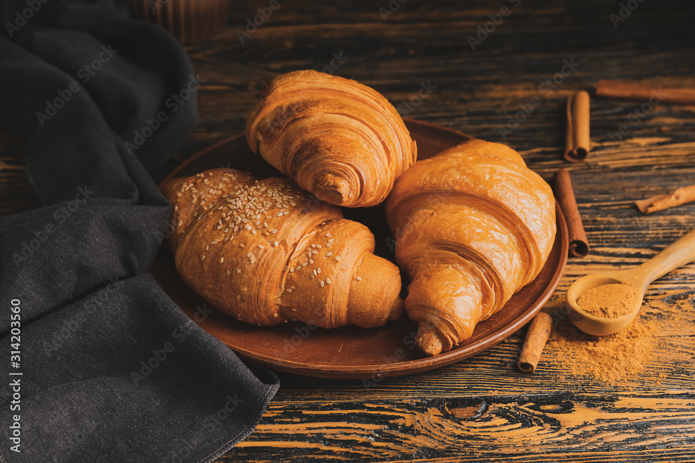 Plate with tasty fresh croissants on table