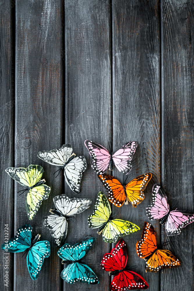 Multicolored tropical butterflies on dark wooden background top-down frame copy space