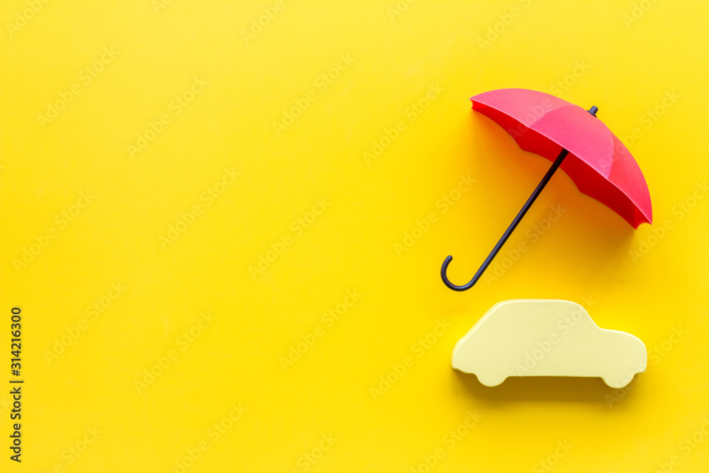 Car protection concept. Automobile cutout defended by umbrella on yellow background top-down copy sp