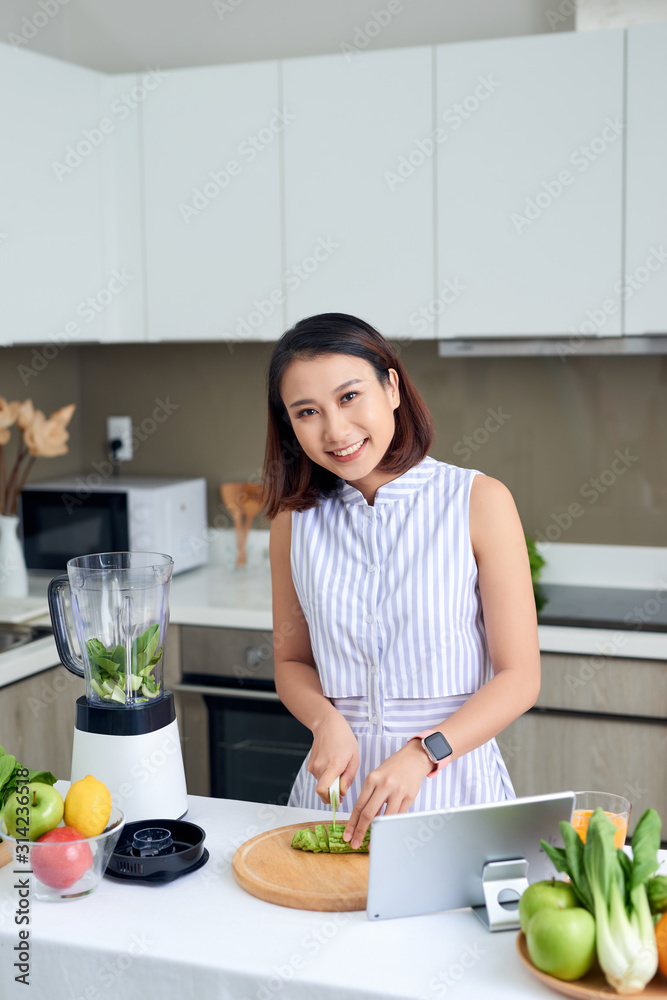 健康的亚洲女性喜欢用搅拌机制作绿色蔬菜排毒清洁和绿色水果奶昔