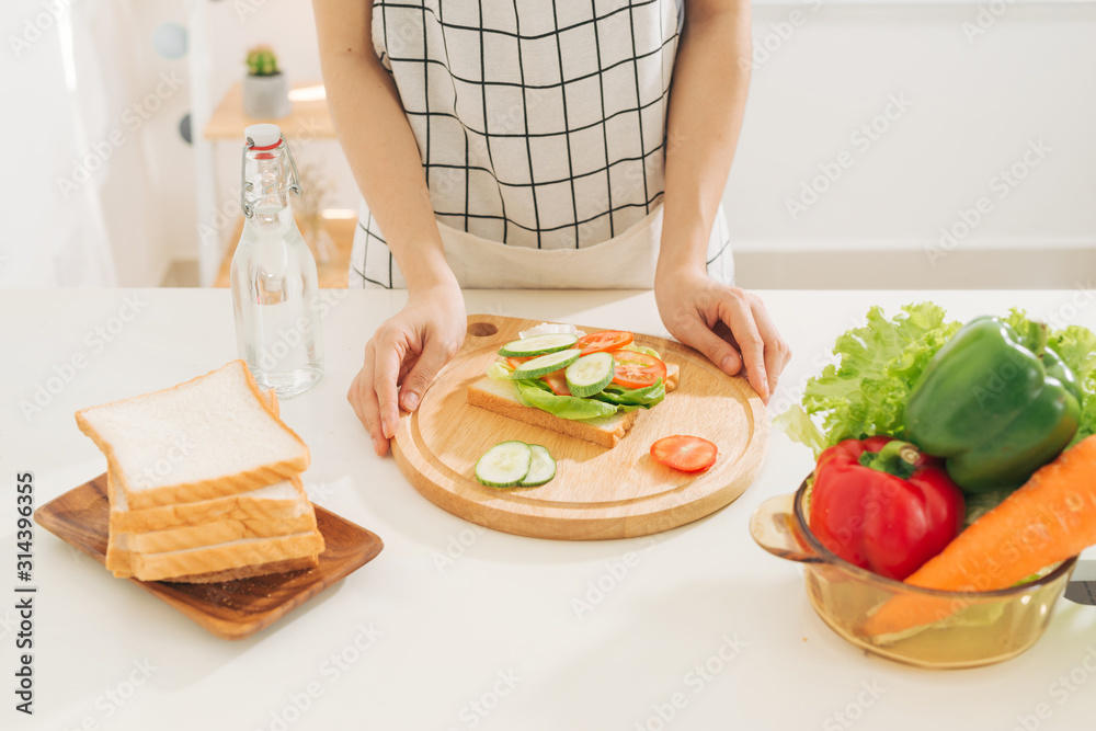 女人正在准备健康的早餐，在厨房里做美味的三明治。良好的节食理念。