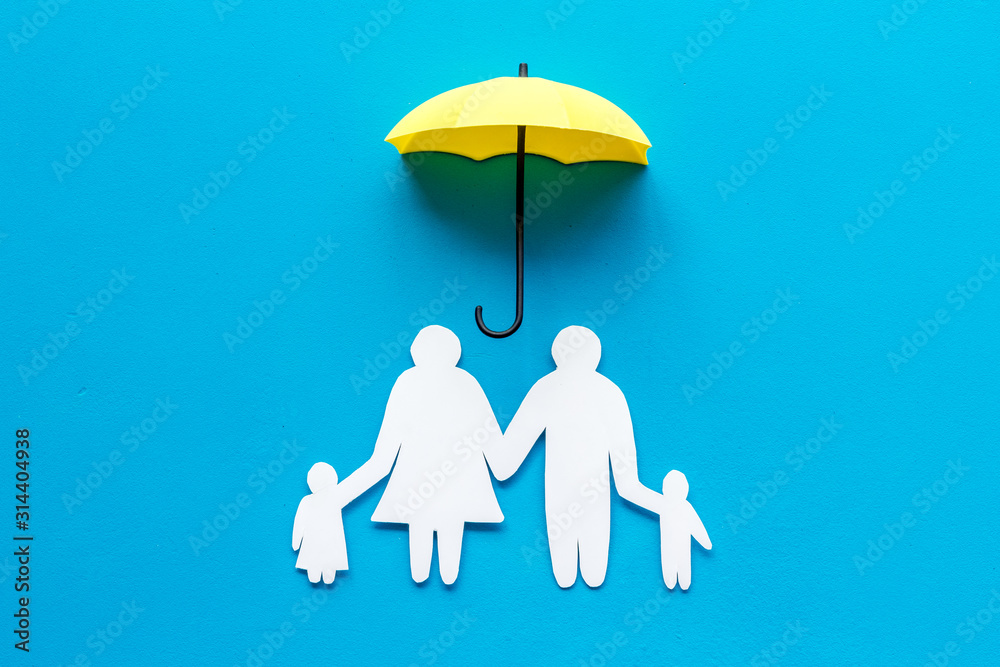 Health insurance concept. Family cutout under umbrella on blue background top-down copy space