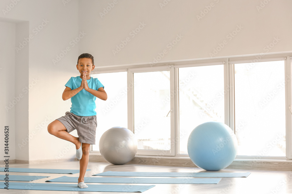 Little African-American boy practicing yoga in gym