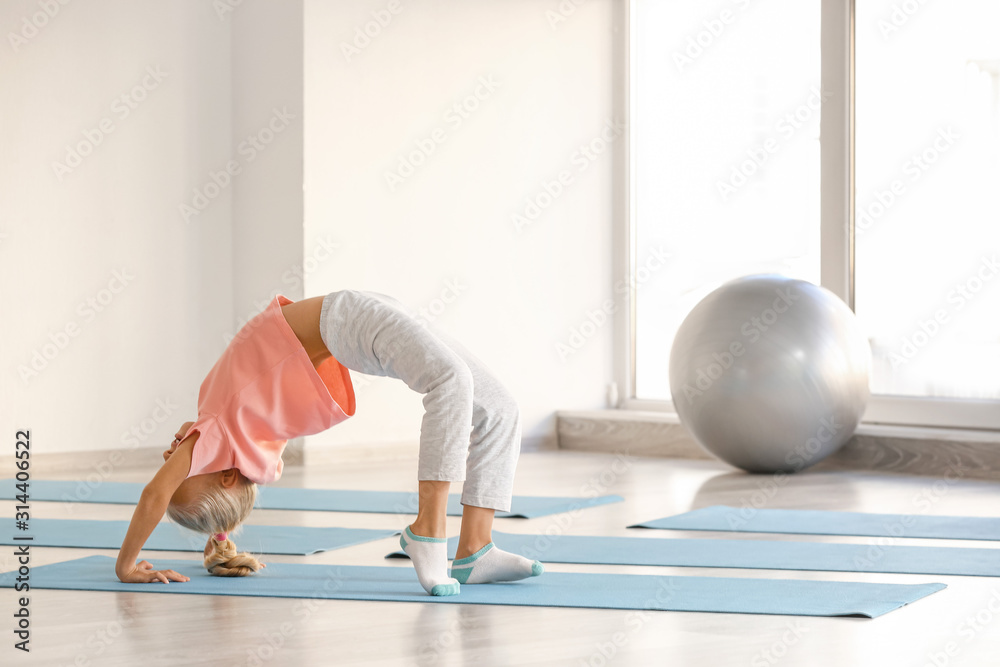 Little girl practicing yoga in gym