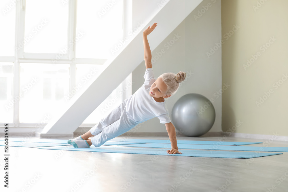 Little girl practicing yoga in gym