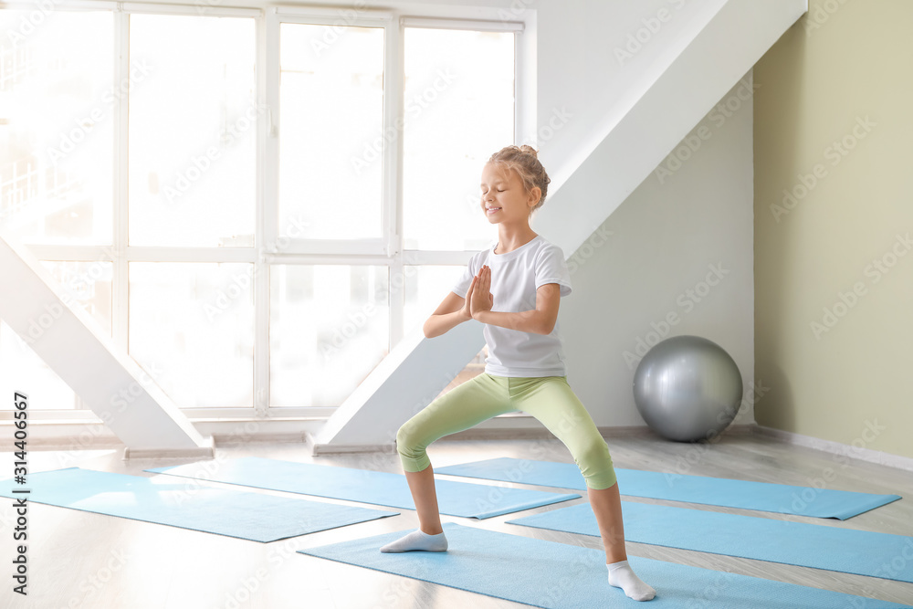 Little girl practicing yoga in gym