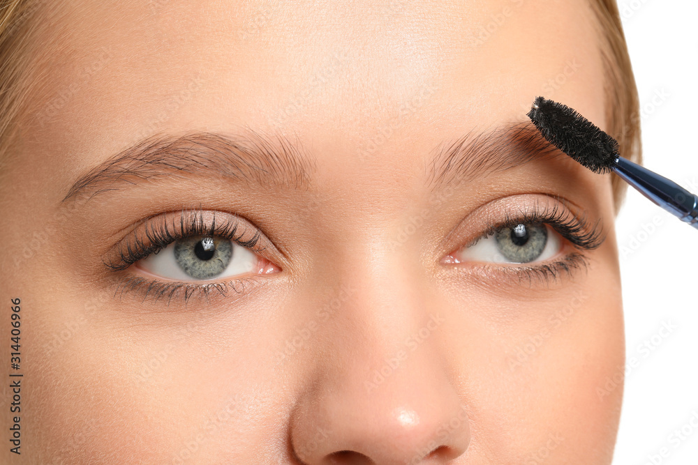 Young woman correcting shape of her eyebrows, closeup