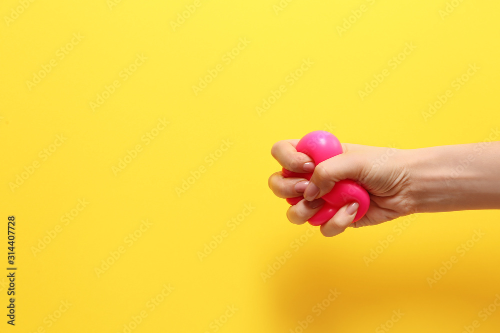 Female hand squeezing stress ball on color background