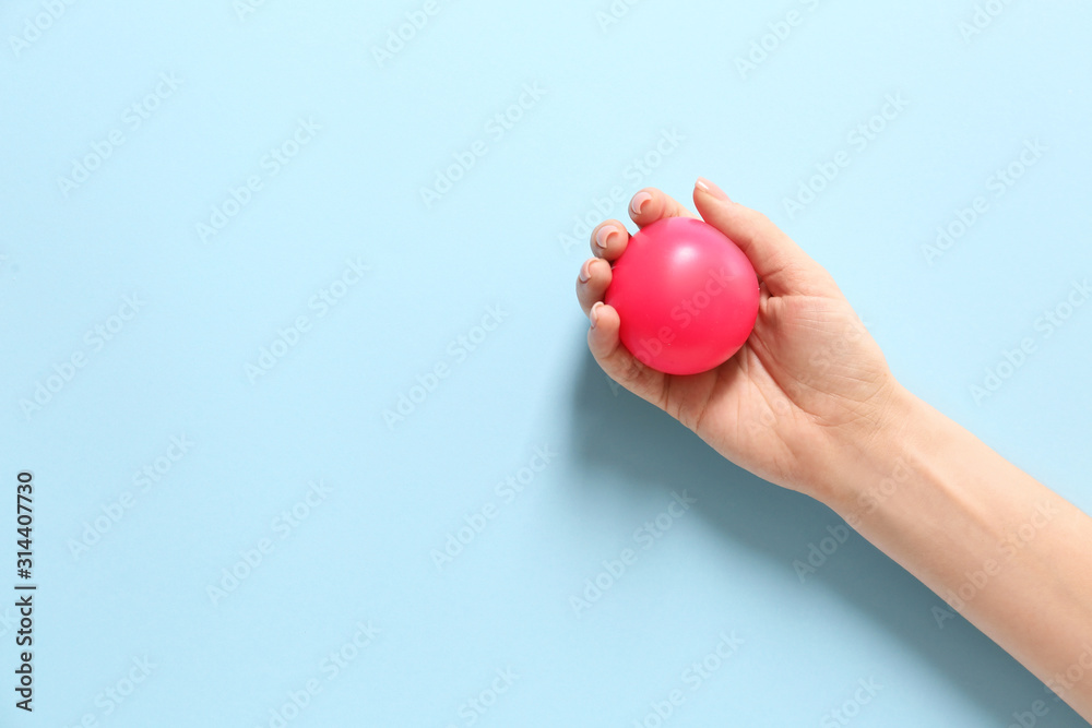 Female hand with stress ball on color background