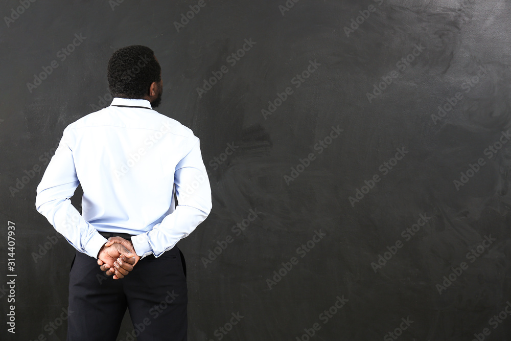 African-American teacher near blackboard in classroom