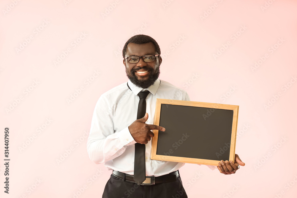 African-American teacher with chalkboard on color background