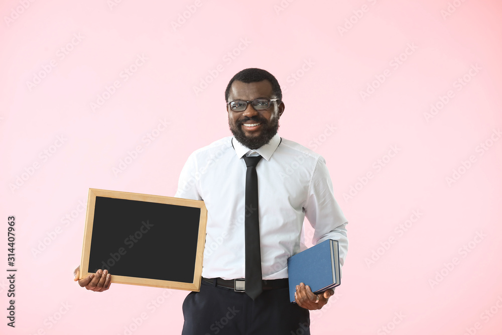 African-American teacher with chalkboard and books on color background