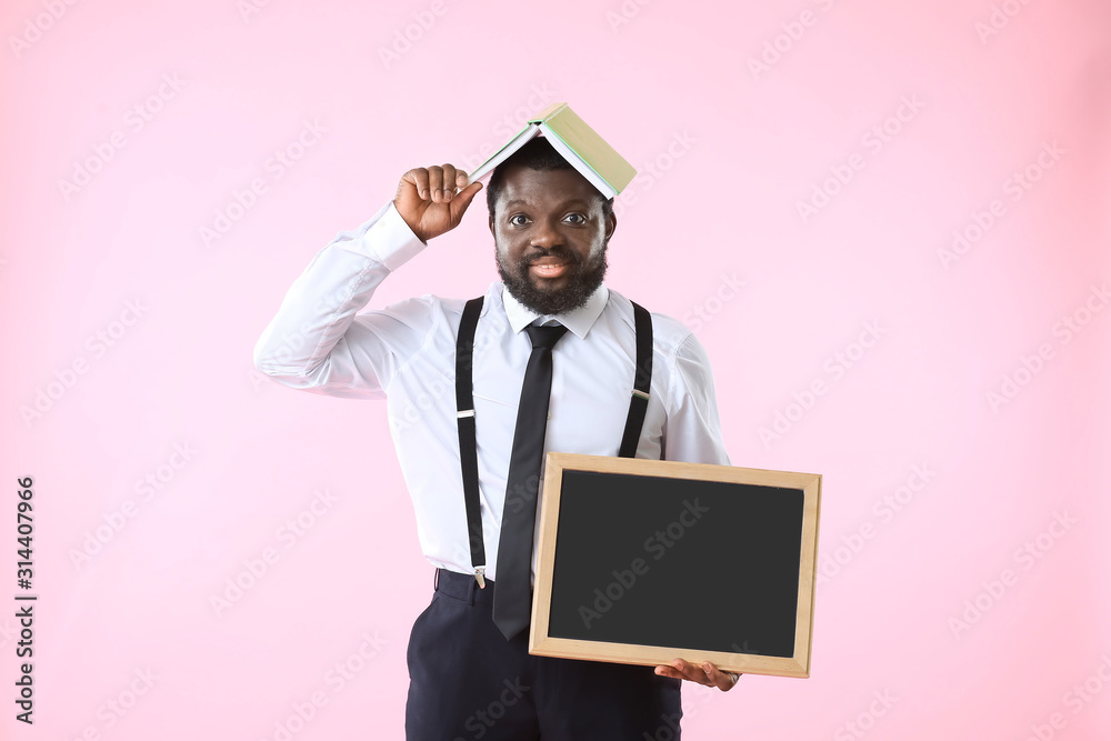 African-American teacher with chalkboard and book on color background