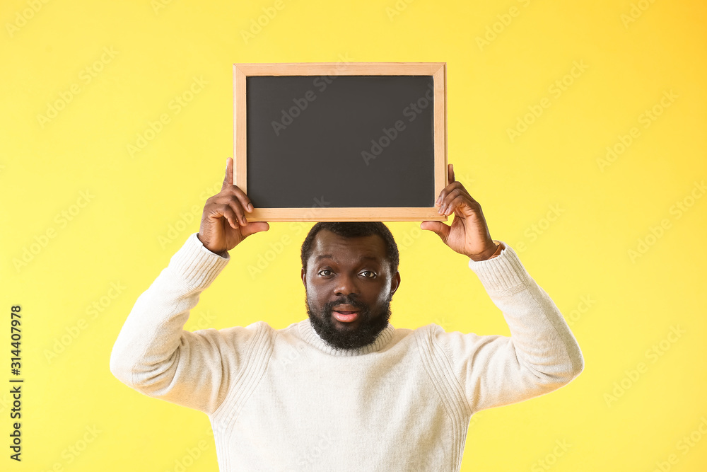 African-American teacher with chalkboard on color background