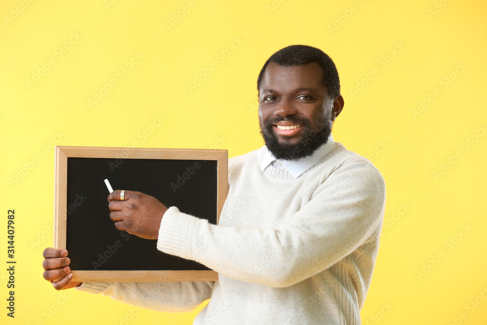 African-American teacher with chalkboard on color background