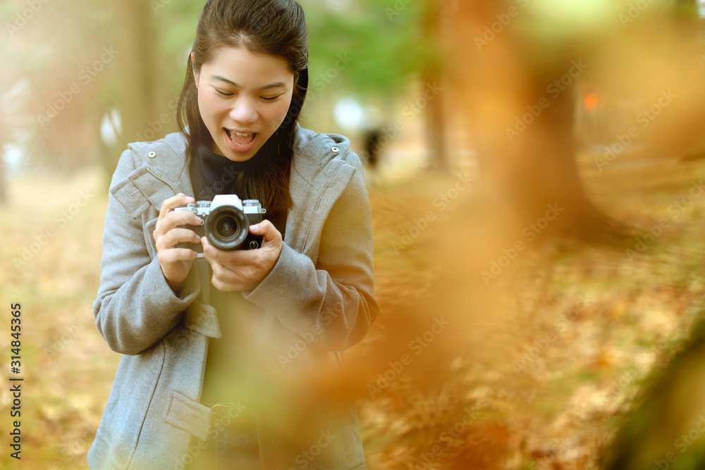 特写亚洲女性用cemera齿轮旅行者，背景是秋天花园的秋天，a