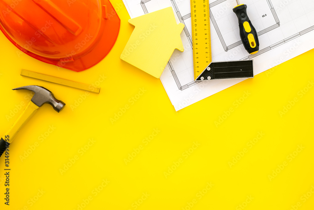 Construction concept. Helmet, instruments, blueprints on yellow background top-down frame copy space