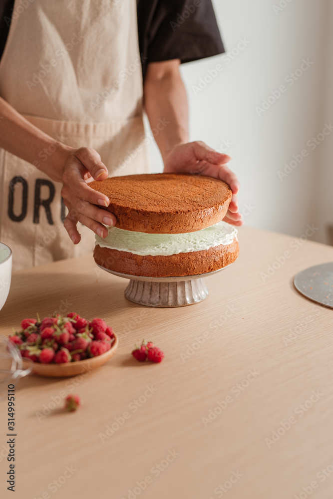 Pastry chef puts cake layer on a cake. Making cake process