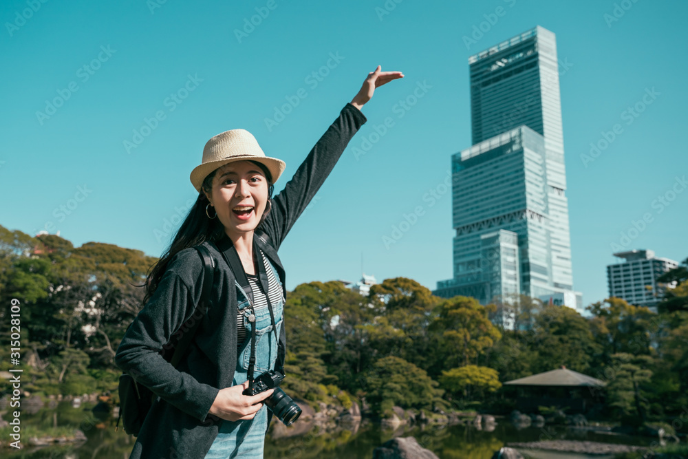 快乐的女摄影师在大阪市abenoku地区与最高的摩天大楼合影。哈