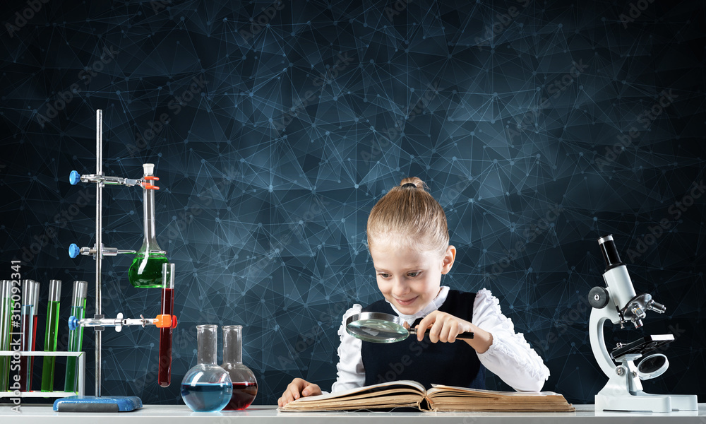 Little girl sitting at desk with magnifier