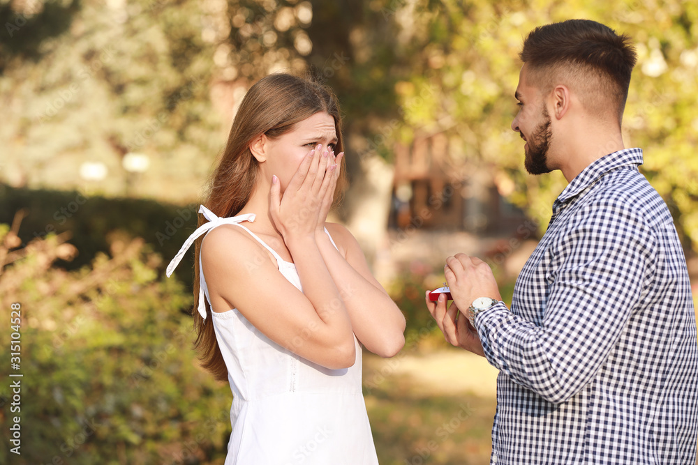 Young man proposing to his beloved outdoors