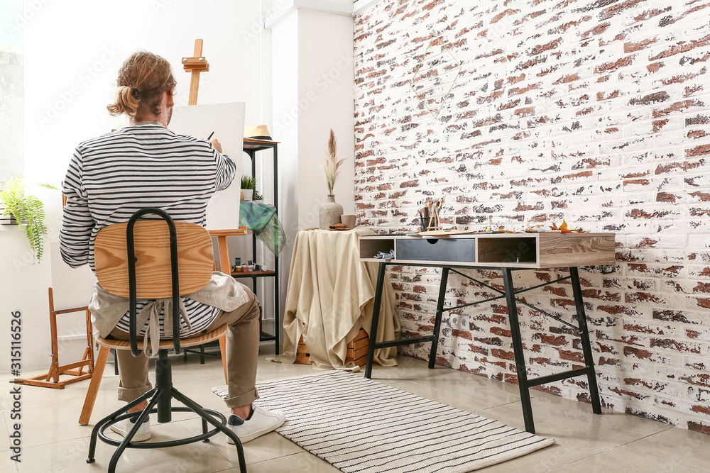 Young male artist painting at home