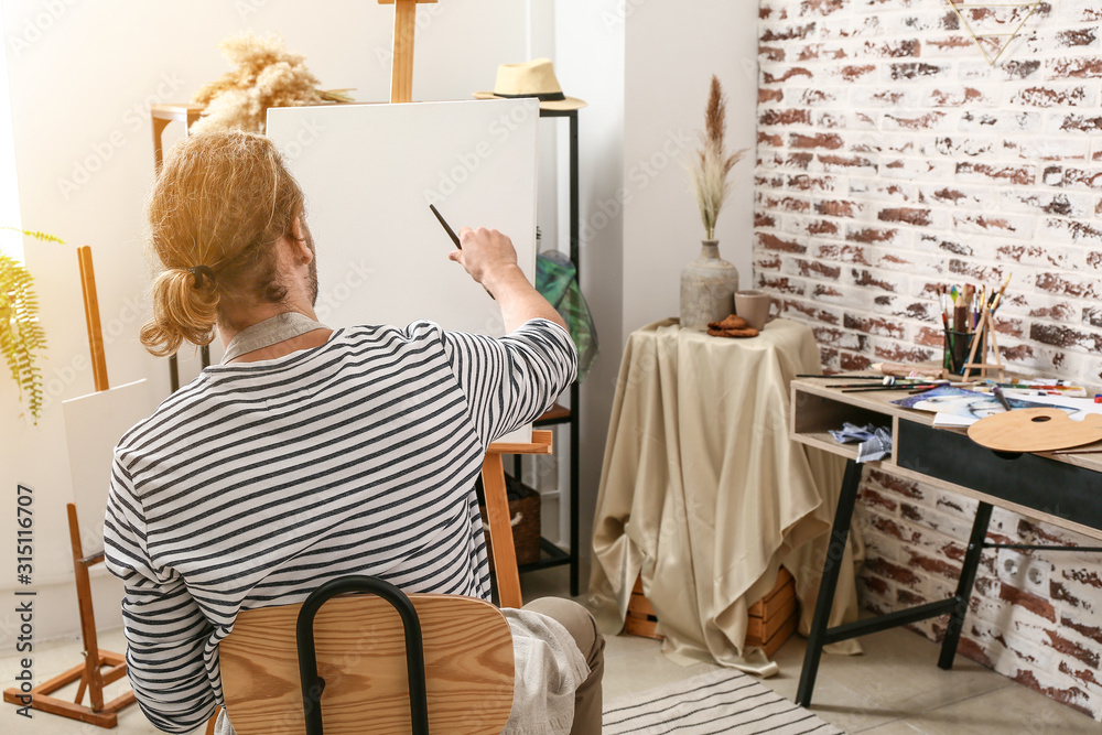 Young male artist painting at home