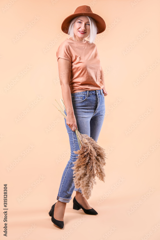 Fashionable mature woman on color background