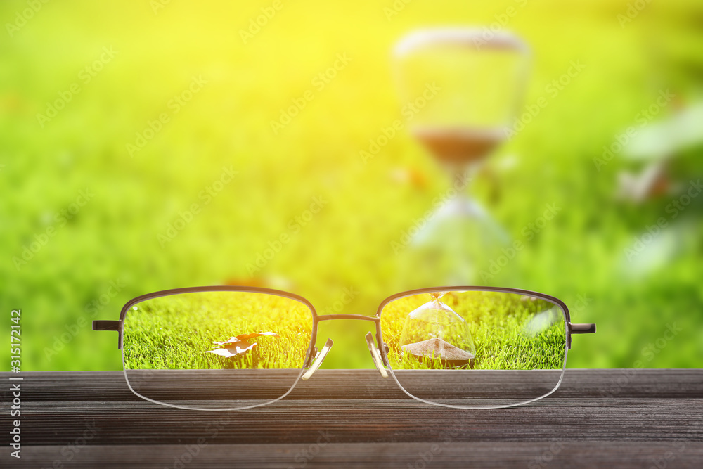 Stylish eyeglasses on wooden table outdoors