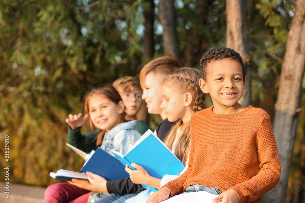 Cute little children reading books in park